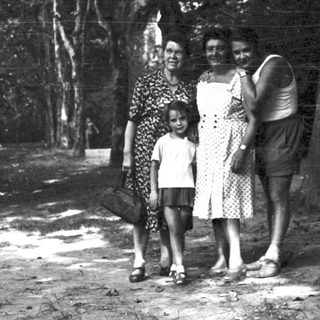 Family posing outdoors in wooded area.