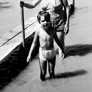 A woman and child walking on a beach pier.