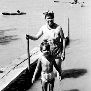 A woman and child walking on a beach pier.
