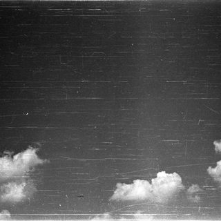 Dark sky with scattered clouds against a building facade.