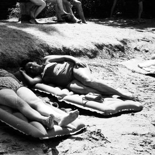 Two people sunbathing on inflatable rafts.
