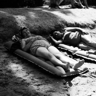 Two people sunbathing on inflatable rafts.