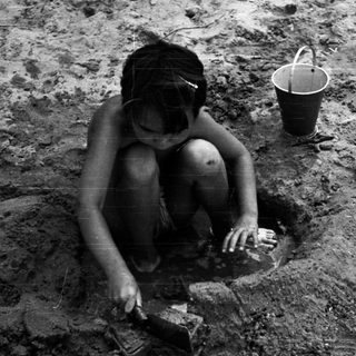 Child digging in muddy ground with tools.