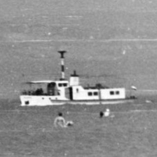 People swimming and boating in coastal waters.