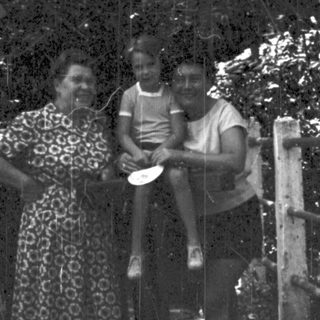 Family posing by a wooden cross in forested area.