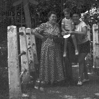 Family posing by a wooden cross in forested area.