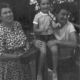 Three people sitting together outdoors in vintage clothing.