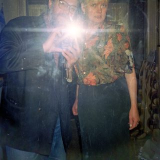 Two people playing phone camera flashlight game indoors.