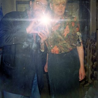 Two people playing phone camera flashlight game indoors.