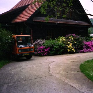 Quaint building with vibrant flowers, parked orange van.