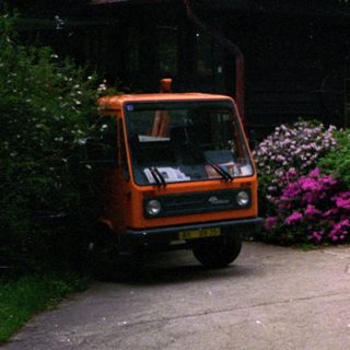 Quaint building with vibrant flowers, parked orange van.
