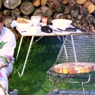 Two people grilling meat over an outdoor fire pit.