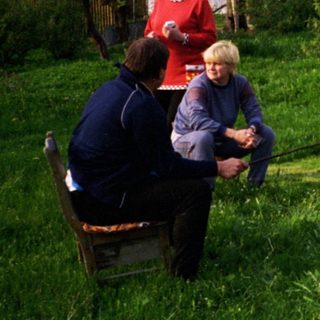 Family gathering around outdoor wood-fired cooking.