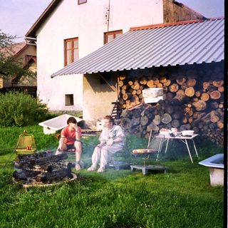 Family gathering around outdoor wood-fired cooking.