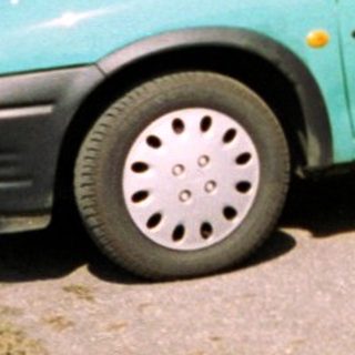 Two people posing beside a turquoise car.