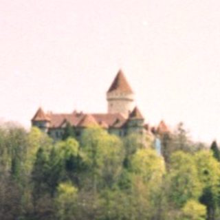 Castle by serene lake surrounded by trees.