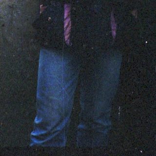 Man standing outdoors in rain wearing purple beanie and jacket.