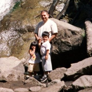 Group hiking near cascading waterfall in rocky terrain.