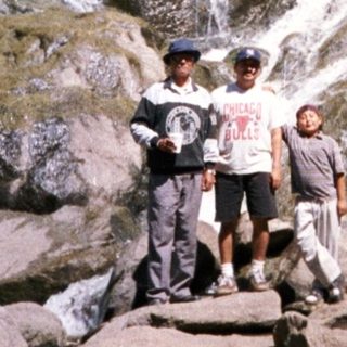 Group hiking near cascading waterfall in rocky terrain.