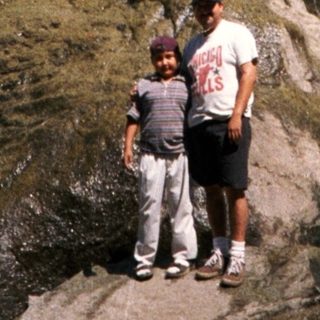 Family enjoying waterfall in natural rocky setting.