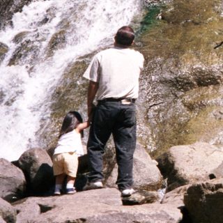 People exploring rocky waterfall area outdoors.