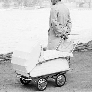 Man pushing a baby buggy near water.