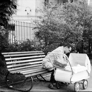 Man pushing stroller, sitting on bench outdoors.