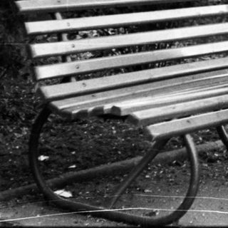 Man pushing stroller, sitting on bench outdoors.
