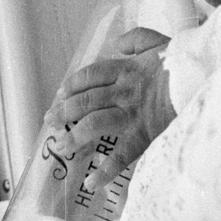 Newborn infant in incubator with "I love you" sign.