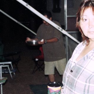 Woman standing near RV holding mugs.