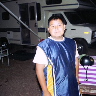 Boy in sports jacket standing near RV campground.