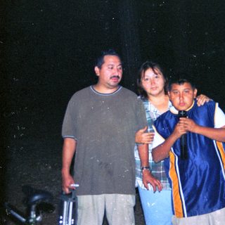 Family group standing outdoors in rain.