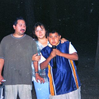 Family group standing outdoors in rain.