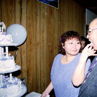 Two people at a wedding reception near a decorated cake.