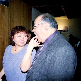 Two people at a wedding reception near a decorated cake.