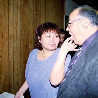 Two people at a wedding reception near a decorated cake.