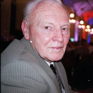 Elderly man in formal attire at evening event.
