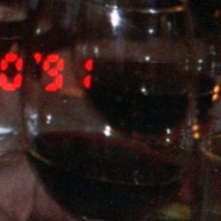 Elderly man drinking wine indoors at evening event.