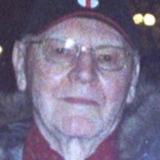 Older man wearing winter coat outdoors at night.