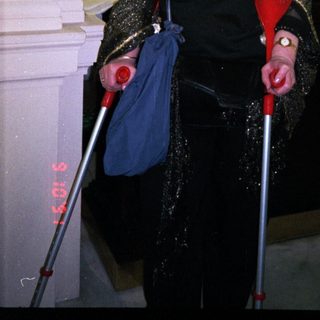Elderly woman using canes indoors at event.