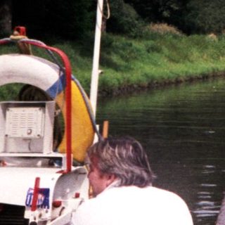 Scenic riverboat passing historic castle by water.