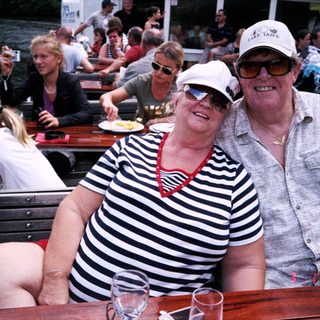 Happy couple enjoying boat river outing with drinks.