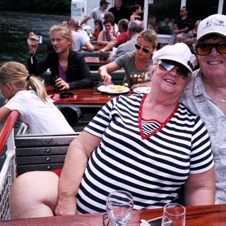 Happy couple enjoying boat river outing with drinks.