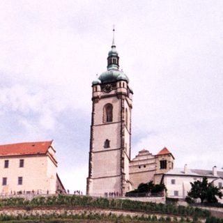 Historic monastery complex with church tower on hillside.