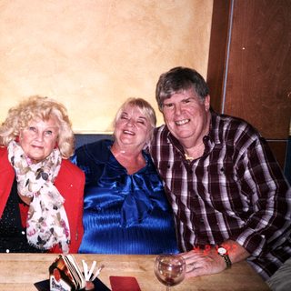 Three people smiling together indoors.