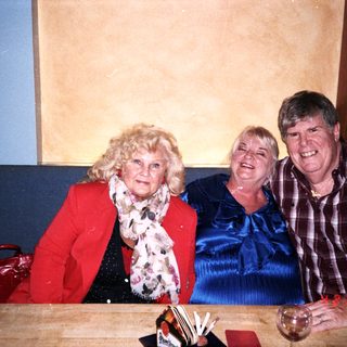 Three people smiling together indoors.