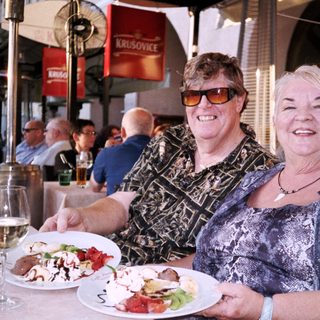 Two women enjoying meal outdoors at café.