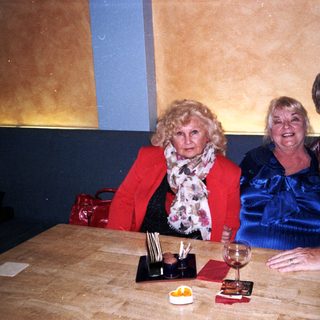 Three adults smiling together indoors at a table.