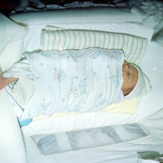 Newborn infant sleeping in hospital bassinet.