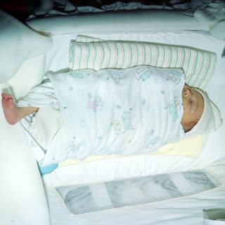 Newborn infant sleeping in hospital bassinet.